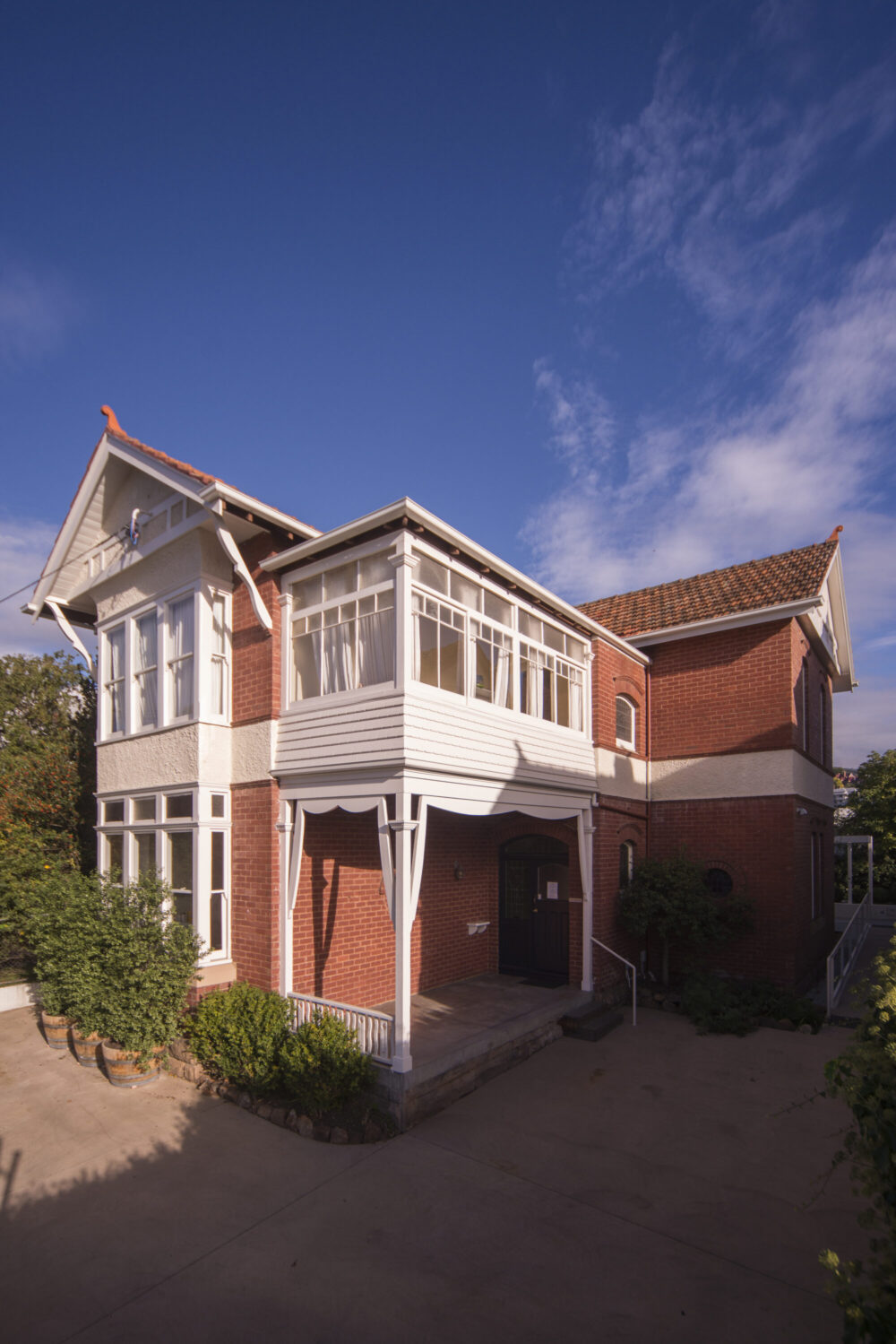 Weatherboard extension to brick building with new timber deck and entry.